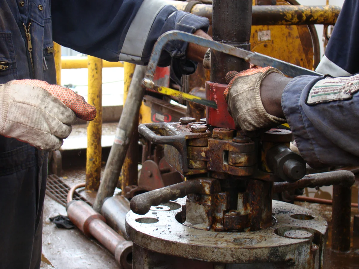 Gloved wellsite technicians working on a well assembly